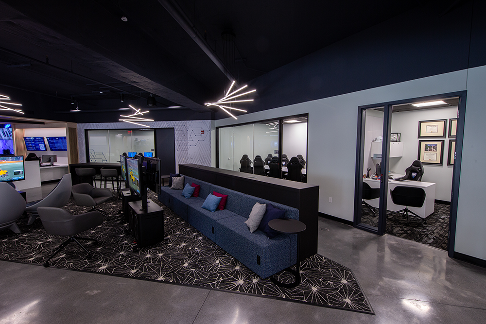 空旷的聚会空间，有蓝色沙发，视频监视器，玻璃会议室.